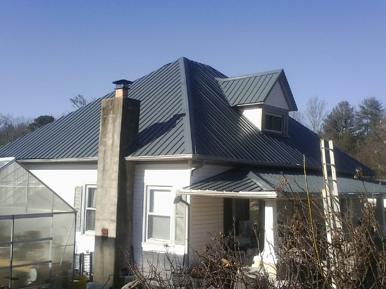 Dark blue standing seam metal roof on a white farmhouse with dormer — Slate & Tile Roof Repair by Roofing Brothers in Lowpoint