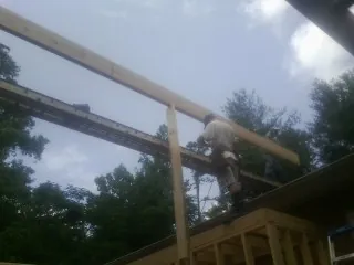 Carpenter setting a ridge beam over a new addition frame — Ice Dam Removal by Roofing Brothers in Lowpoint