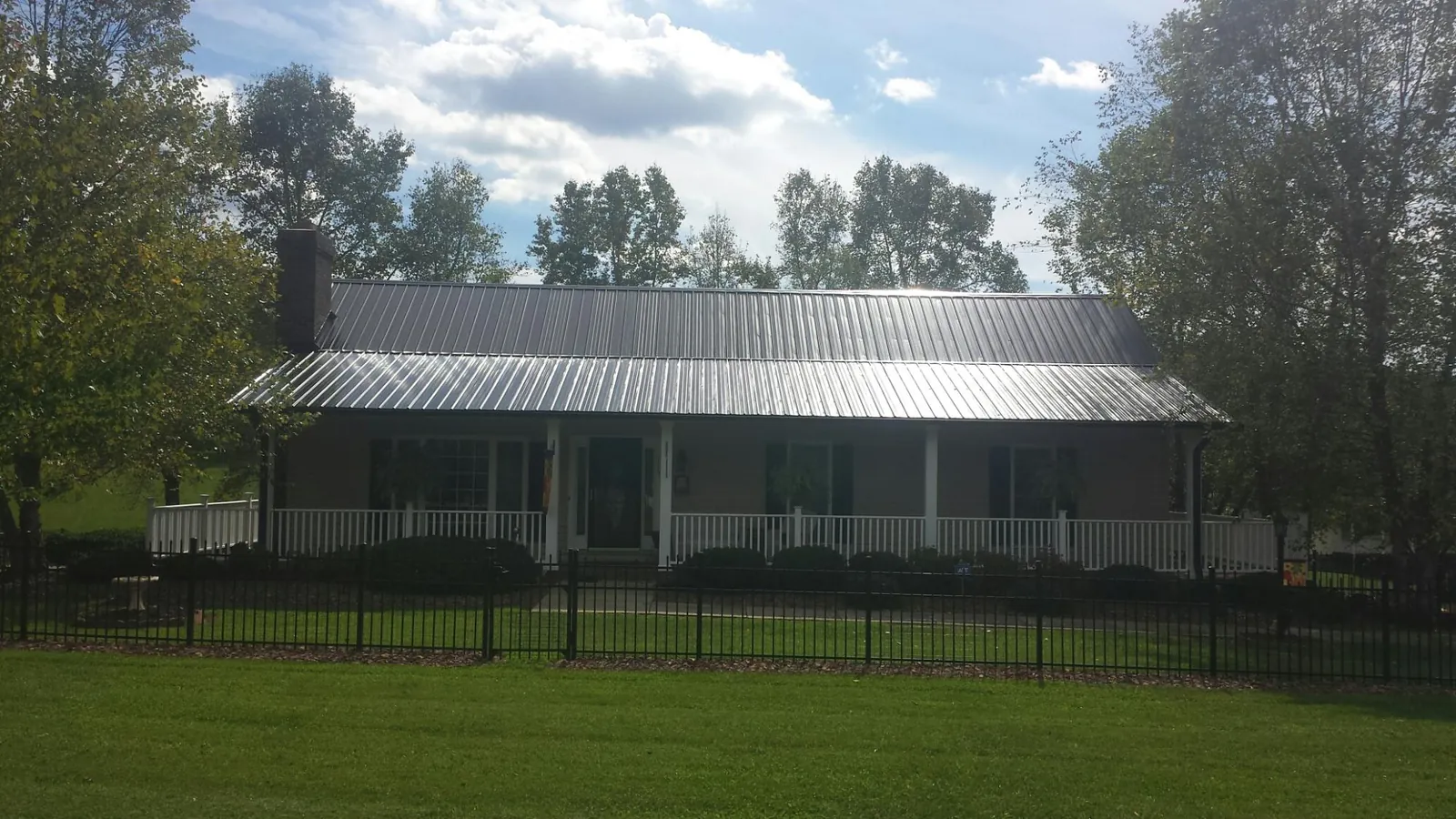 Gray metal roof on a brick ranch with a full width front porch — Gutter Guard Installation work by our crew in Lowpoint