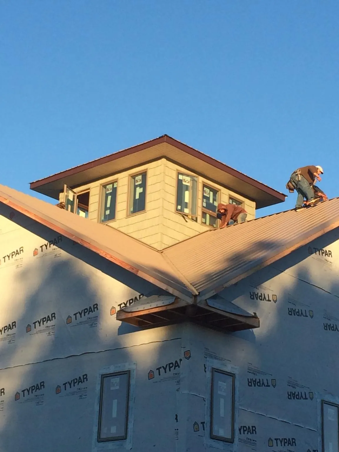 Roofers working around a rooftop cupola on a new metal roof at sunset — Roof Waterproofing in Lowpoint by Roofing Brothers